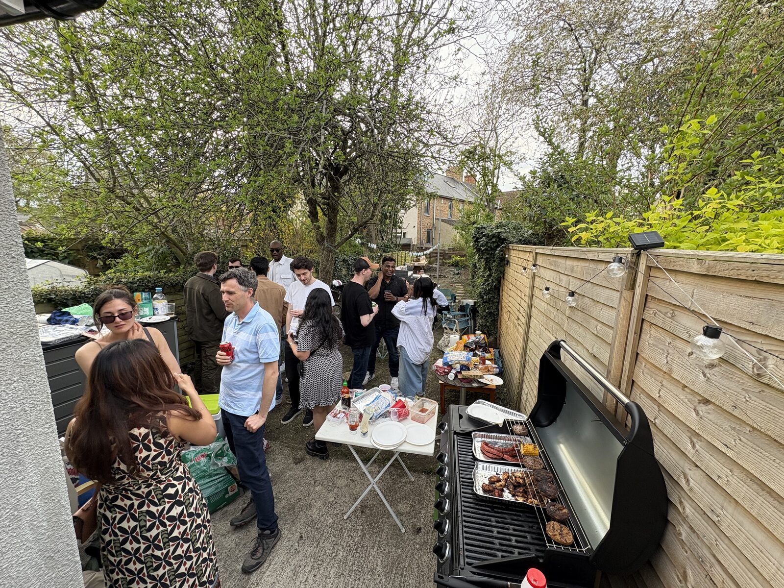 People chatting beside a barbecue in a garden