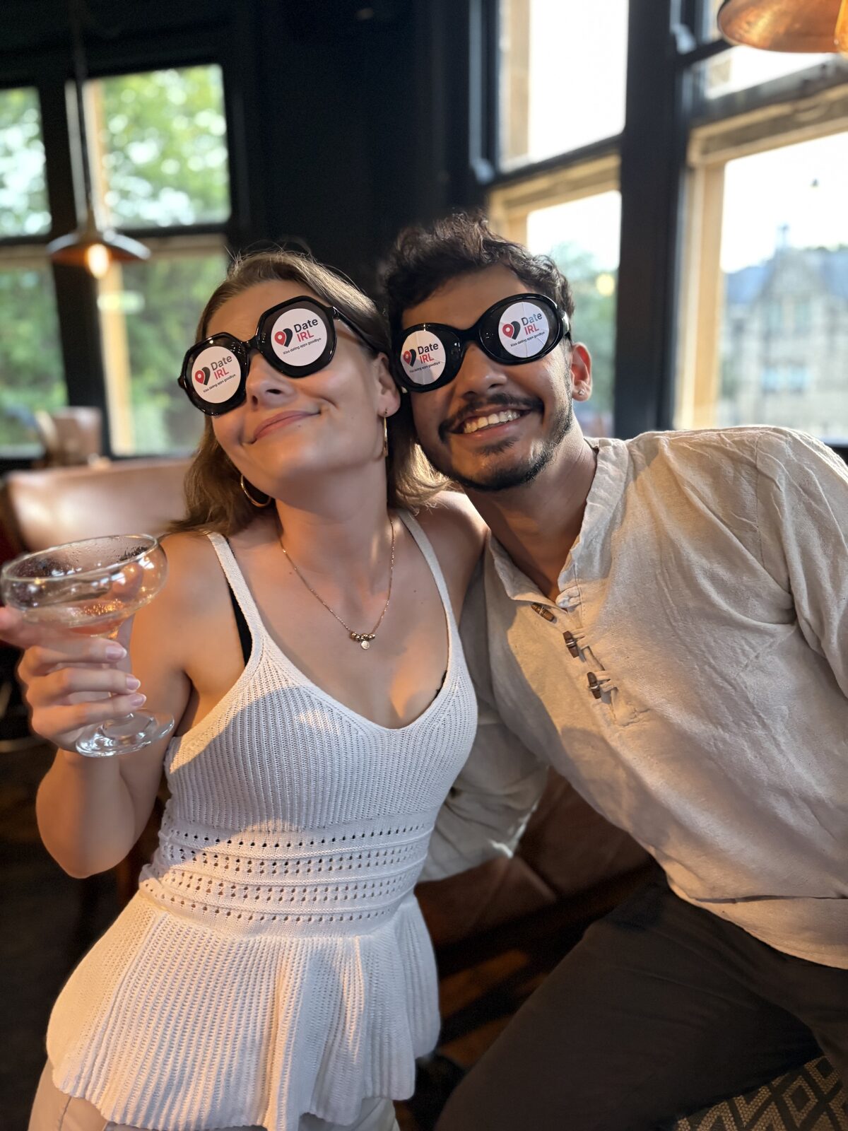 Two people posing together wearing Date IRL novelty glasses