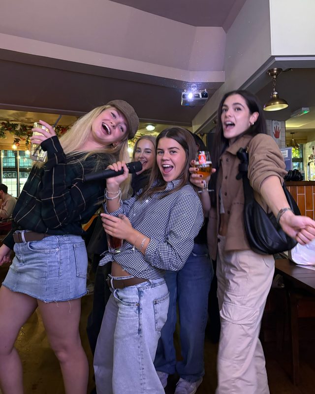 Four people singing karaoke together with a microphone