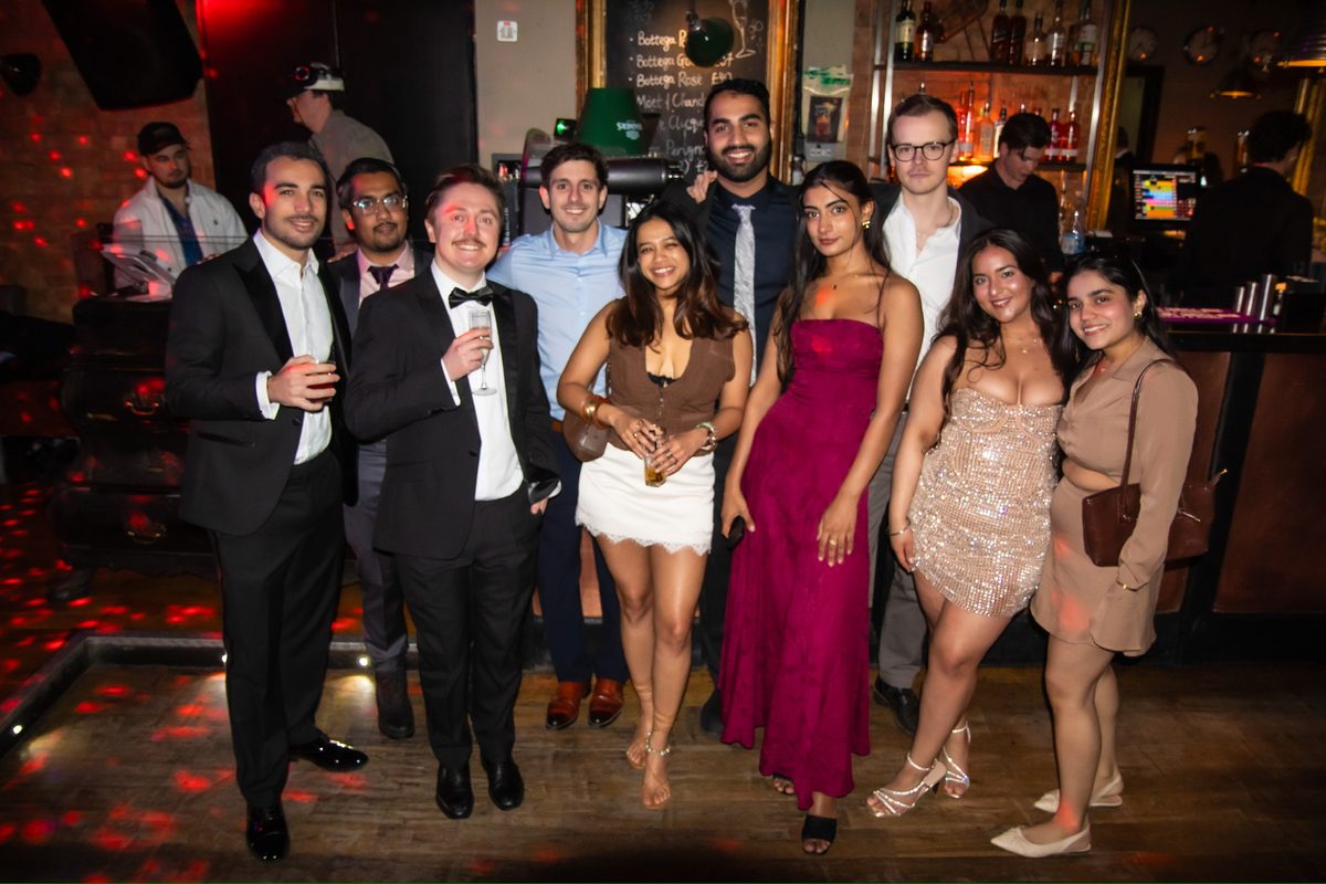 A group posing together in formal outfits at an indoor event