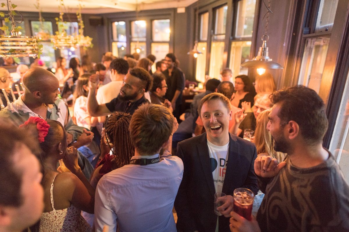 A crowd chatting and smiling at an indoor event