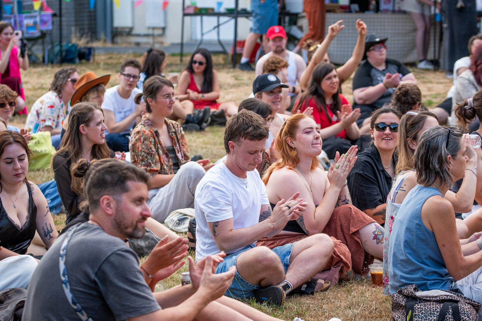 People sitting on the grass and applauding at an outdoor event