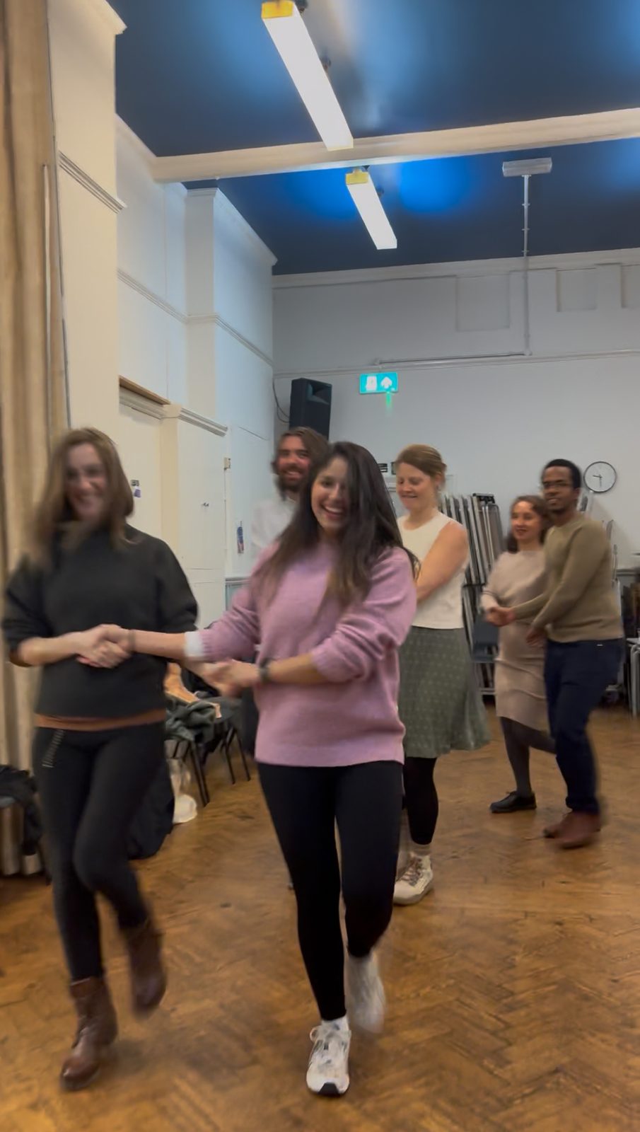 People holding hands and dancing together at a ceilidh